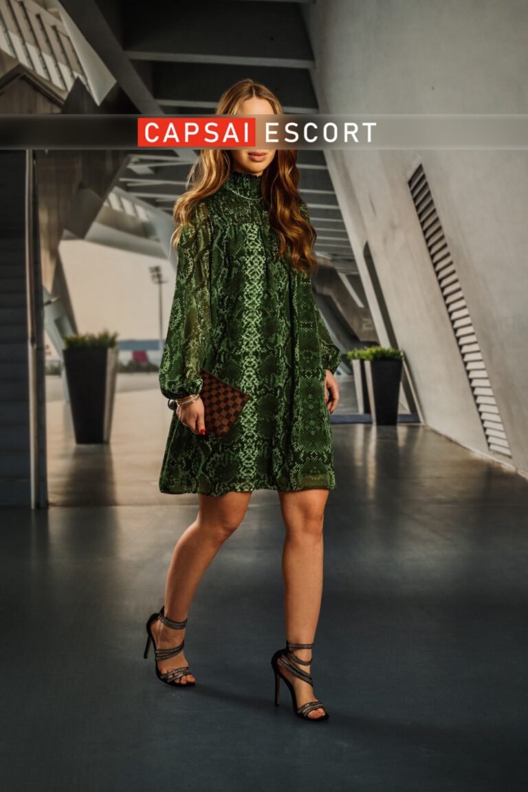 Escort Dame Anina in einem grünen Kleid mit High Heels.