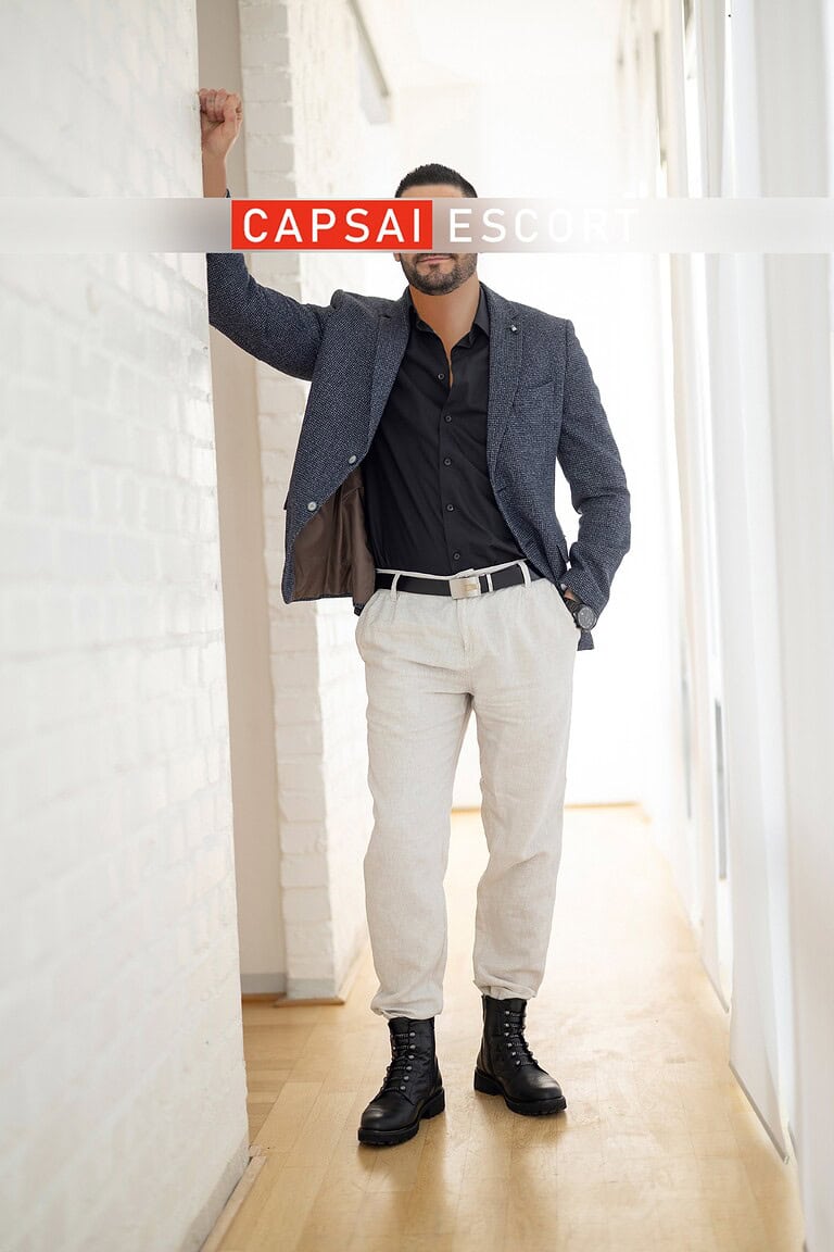 Callboy Carlos in einem schwarzen Hemd mit blauen Sakko und heller Hose.