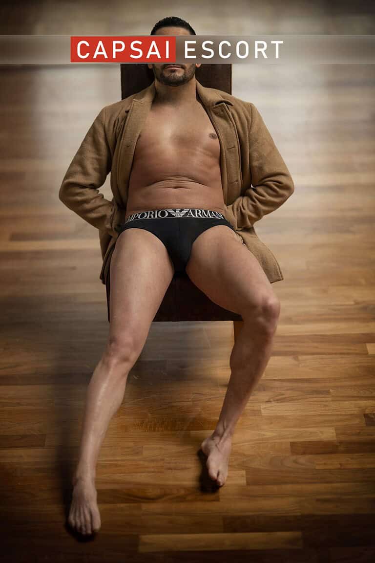 Callboy Carlos in Unterwäsche und offenem Hemd auf dem Stuhl liegend.