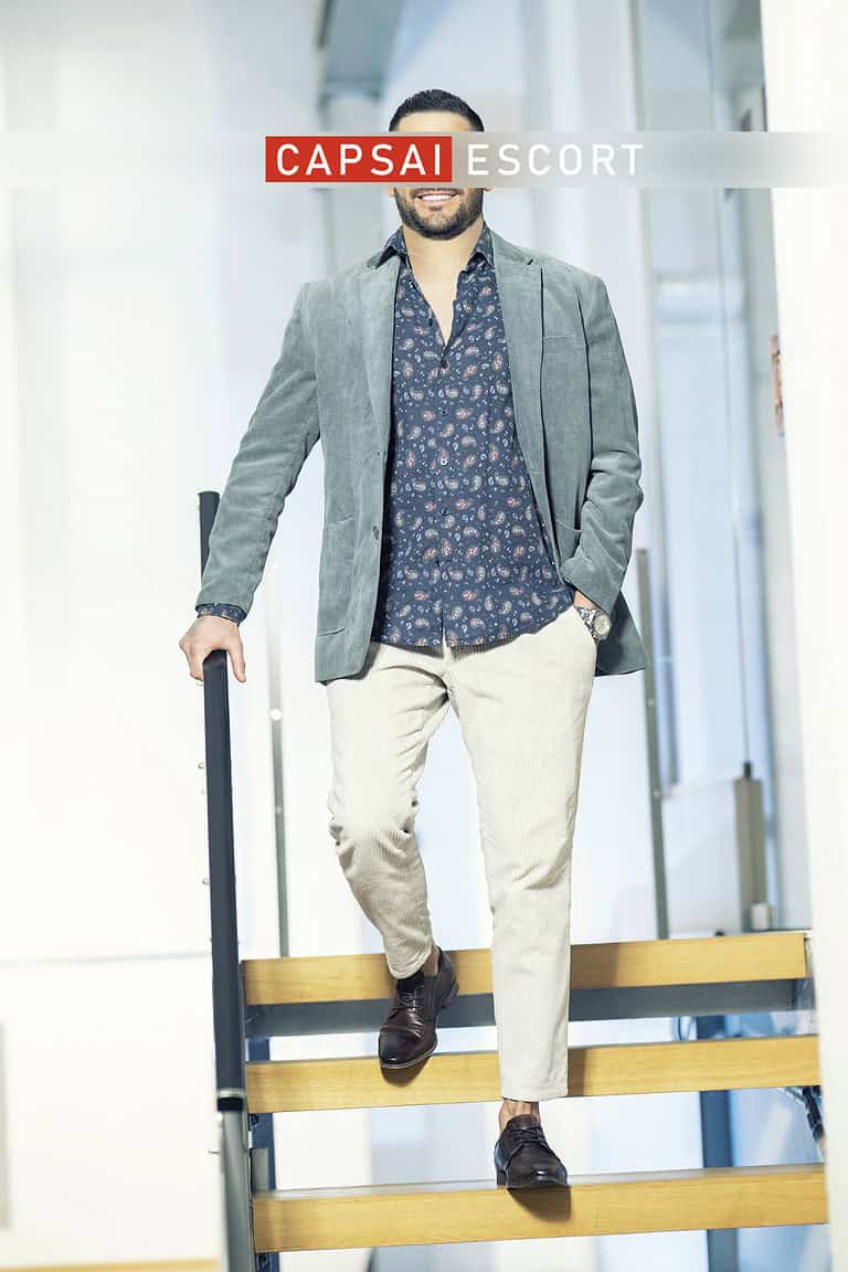 Callboy Carlos im Hemd, Sakko und Chinohose auf der Treppe stehend.