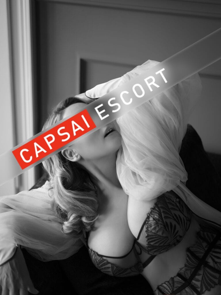 Escort Dame Freya in schwarz/beigen Dessous und schwarzen und einem langen Morgenmantel liegend.