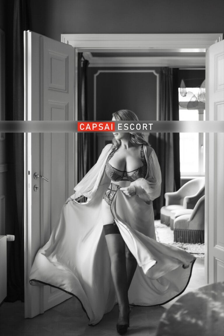 Escort Dame Freya in schwarz/beigen Dessous und schwarzen Nylons mit High Heel und einem langen Morgenmantel.