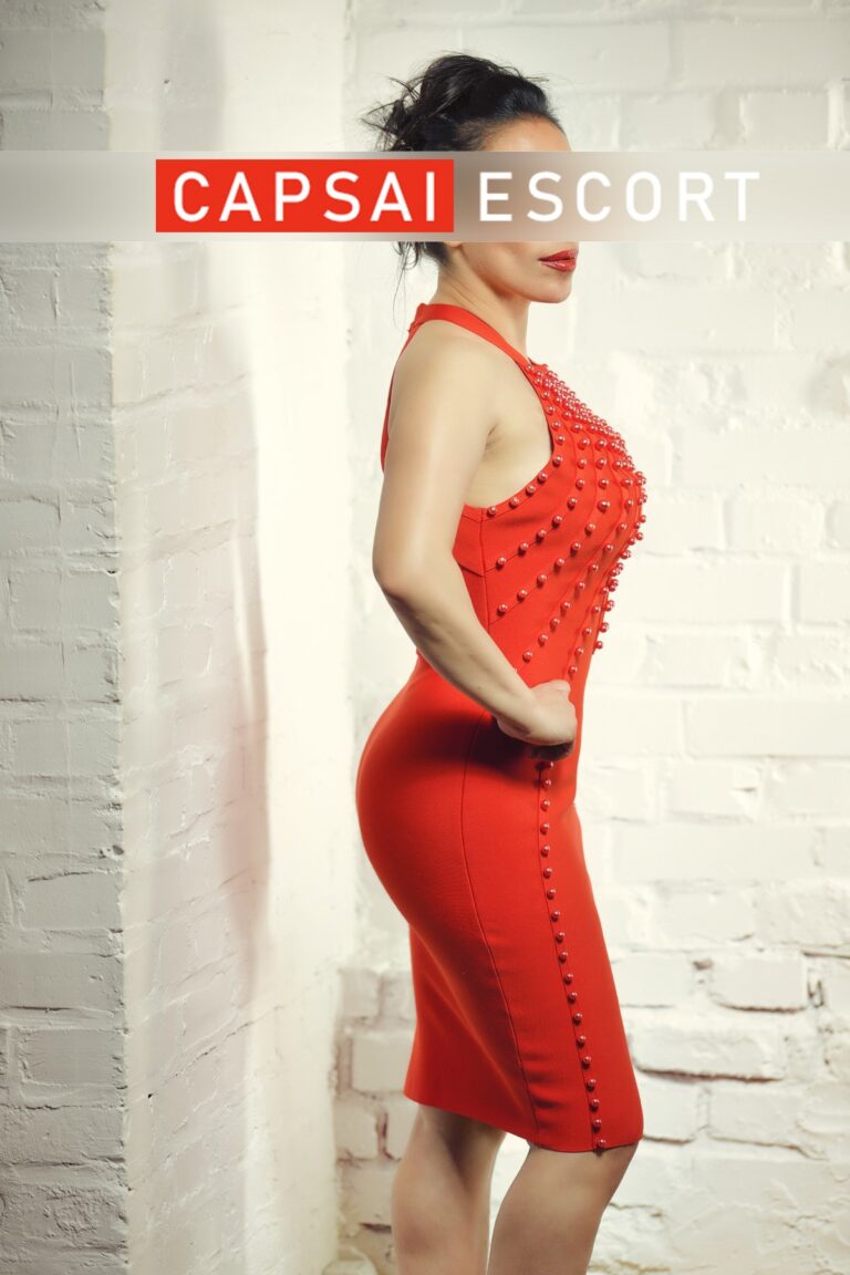 Escort Dame Lara in einem roten Kleid in Seitenansicht.