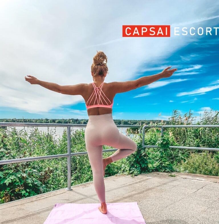 Escort Dame Luisa in Sport BH und Leggings in Yoga Pose draußen mit Ansicht von hinten.