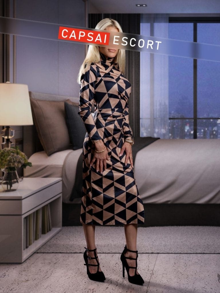 Escort Dame Paulina in einem schwarz/beigen Kleid mit schwarzen High Heels.